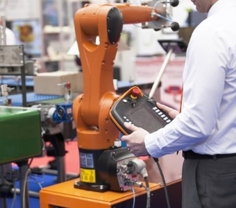 A man is standing next to a robot in a factory.
