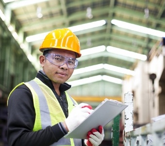 Asian worker holding a clipboard in a factory.