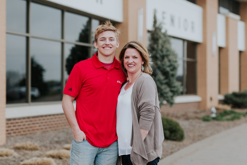 Grant and his mother pose for a photo outside of Grant's high school following him signing his scholarship.