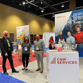 A group of people standing in front of a csw services booth.