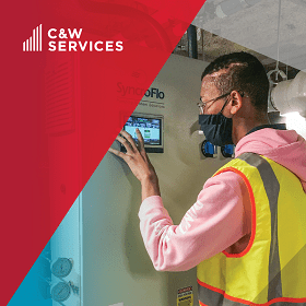 A man in a vest is working on a machine with the words caw services.