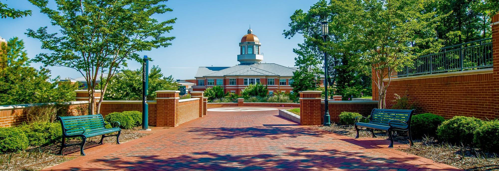 A brick walkway leads to a brick building with a clock tower.