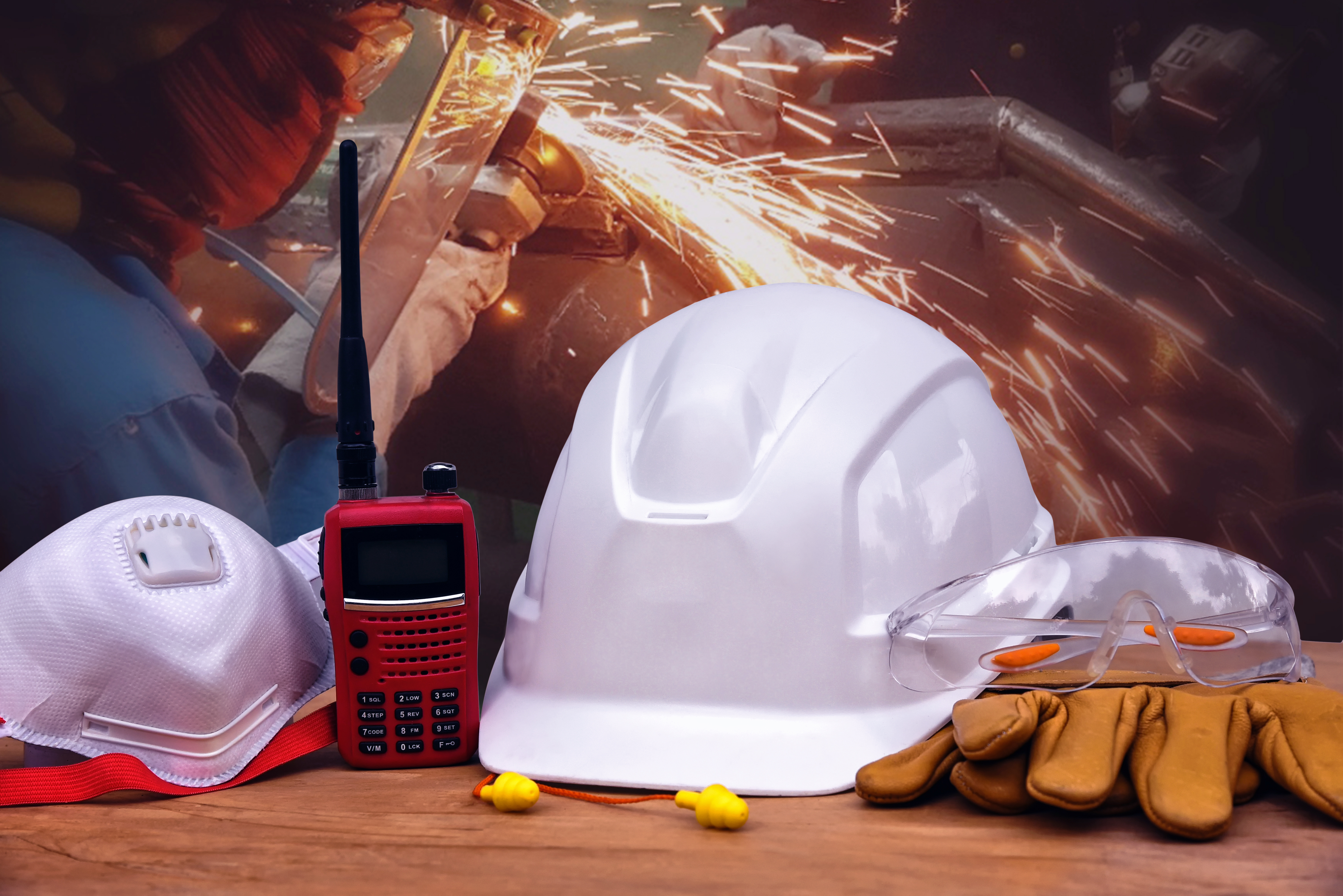 Safety Equipment next to construction worker cutting metal with grinder