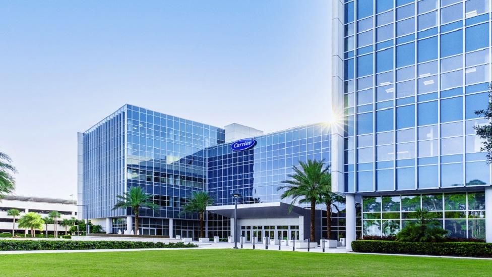 A large office building with grass and palm trees.