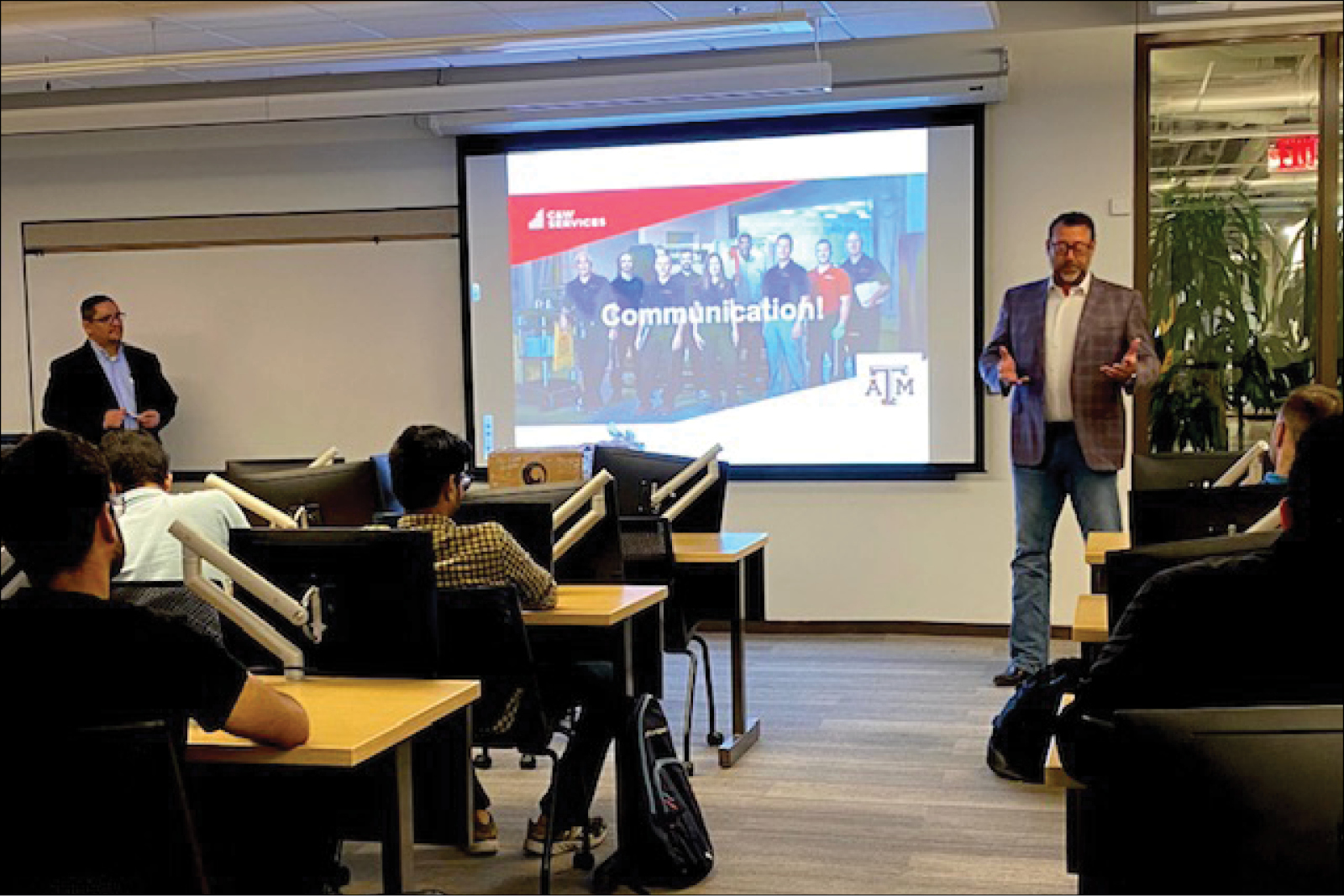 A man is giving a presentation to a group of people in a classroom.