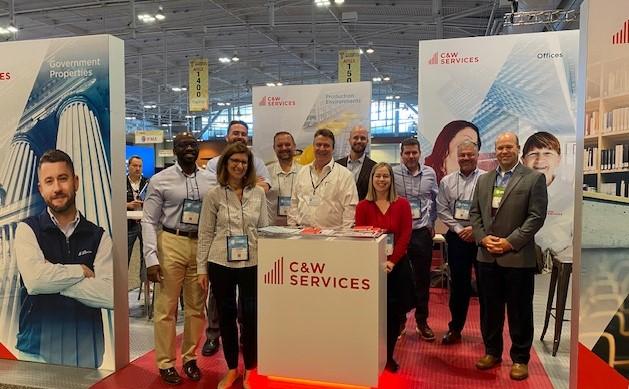 A group of people standing in front of a clw services booth.
