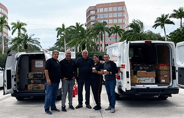 A group of people standing next to a van full of food.