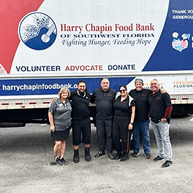 Harry chipp food bank volunteers pose in front of a truck.