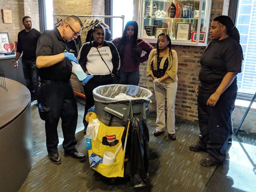 A group of people standing around a trash can.