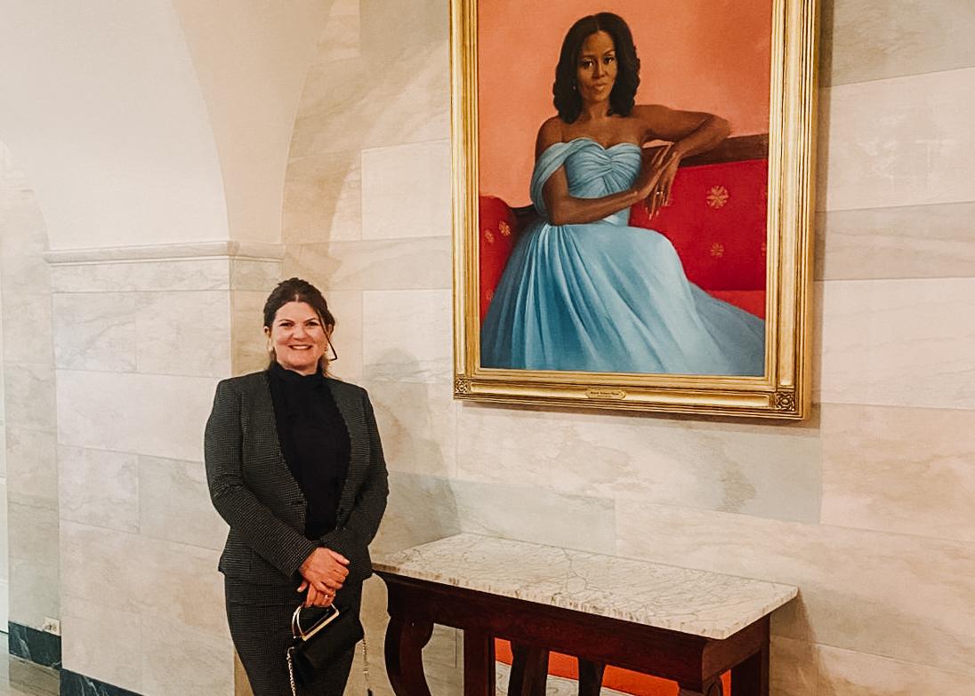 A woman standing in front of a painting of obama.
