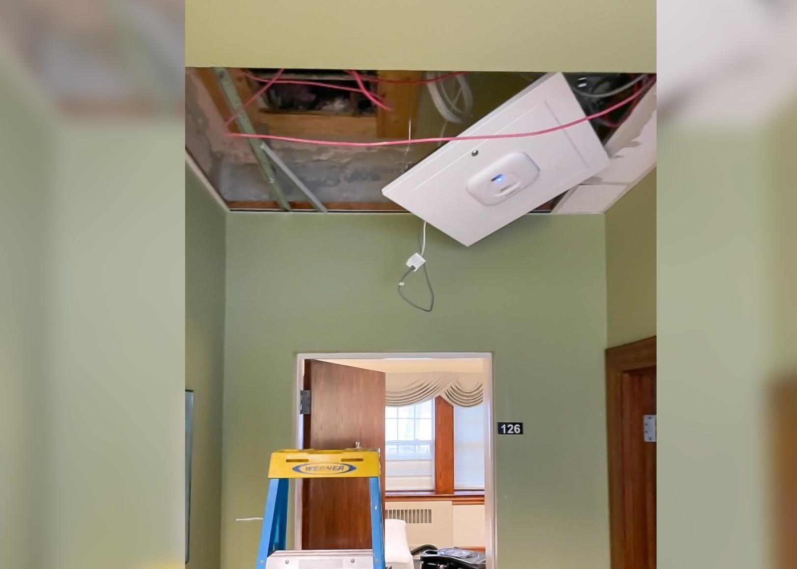 An air conditioning unit is hanging from the ceiling in a room.