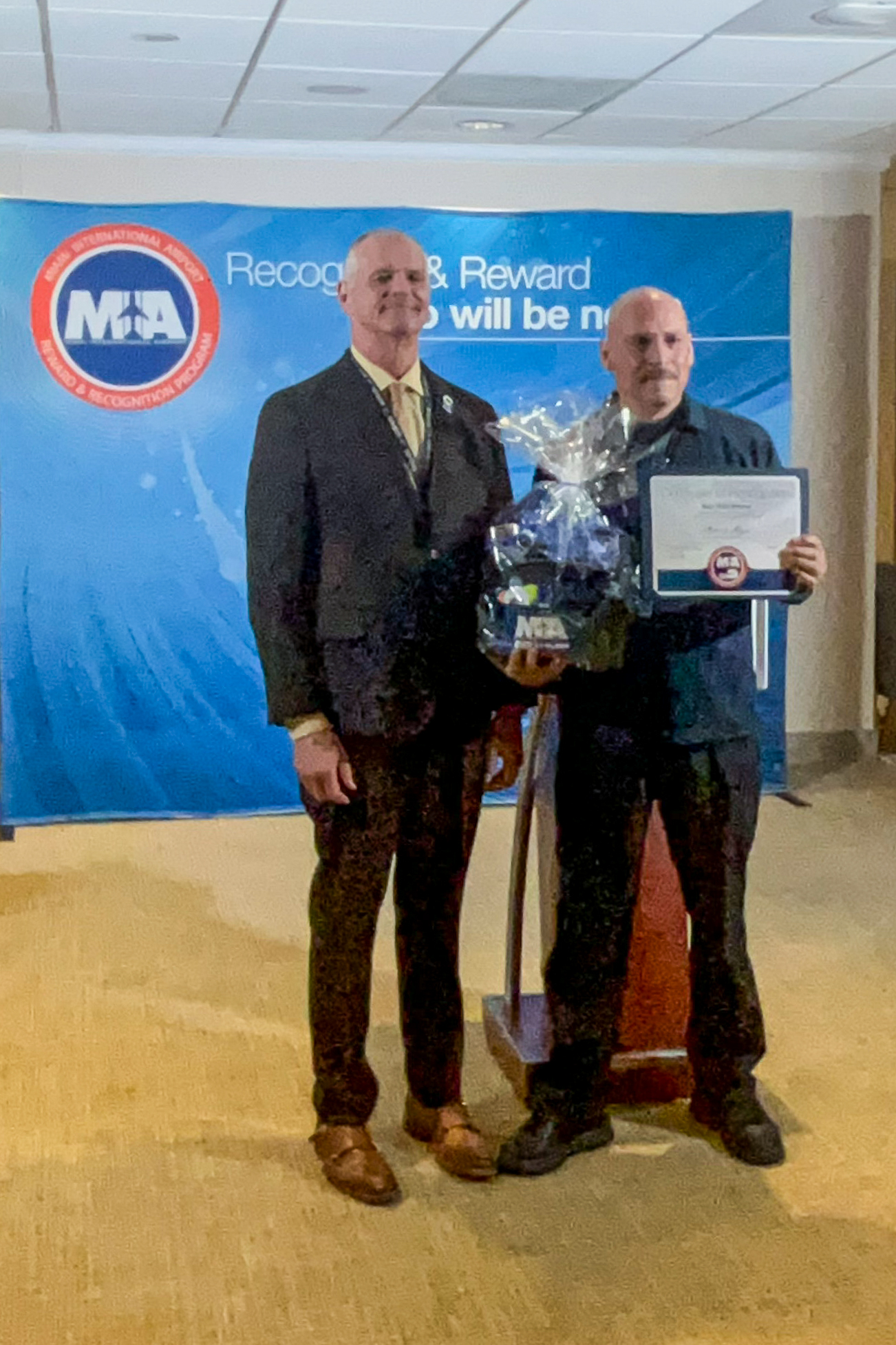 Two men standing next to each other holding a certificate.