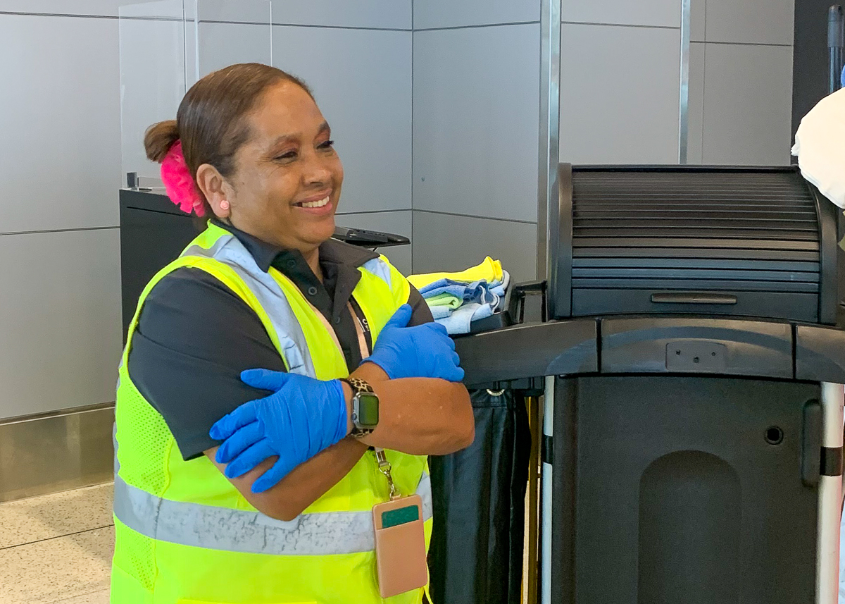 A smiling woman wearing a safety vest and gloves