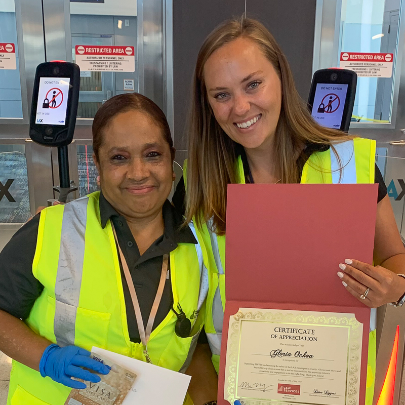 Two women in vests posing for a photo with a certificate.