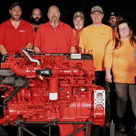 A group of people standing next to a red engine.