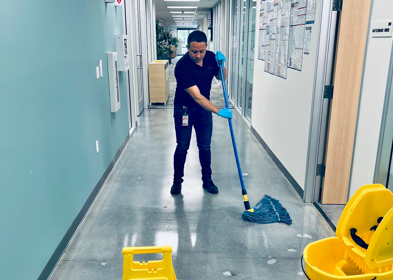 A woman cleaning a hallway with a mop and bucket.