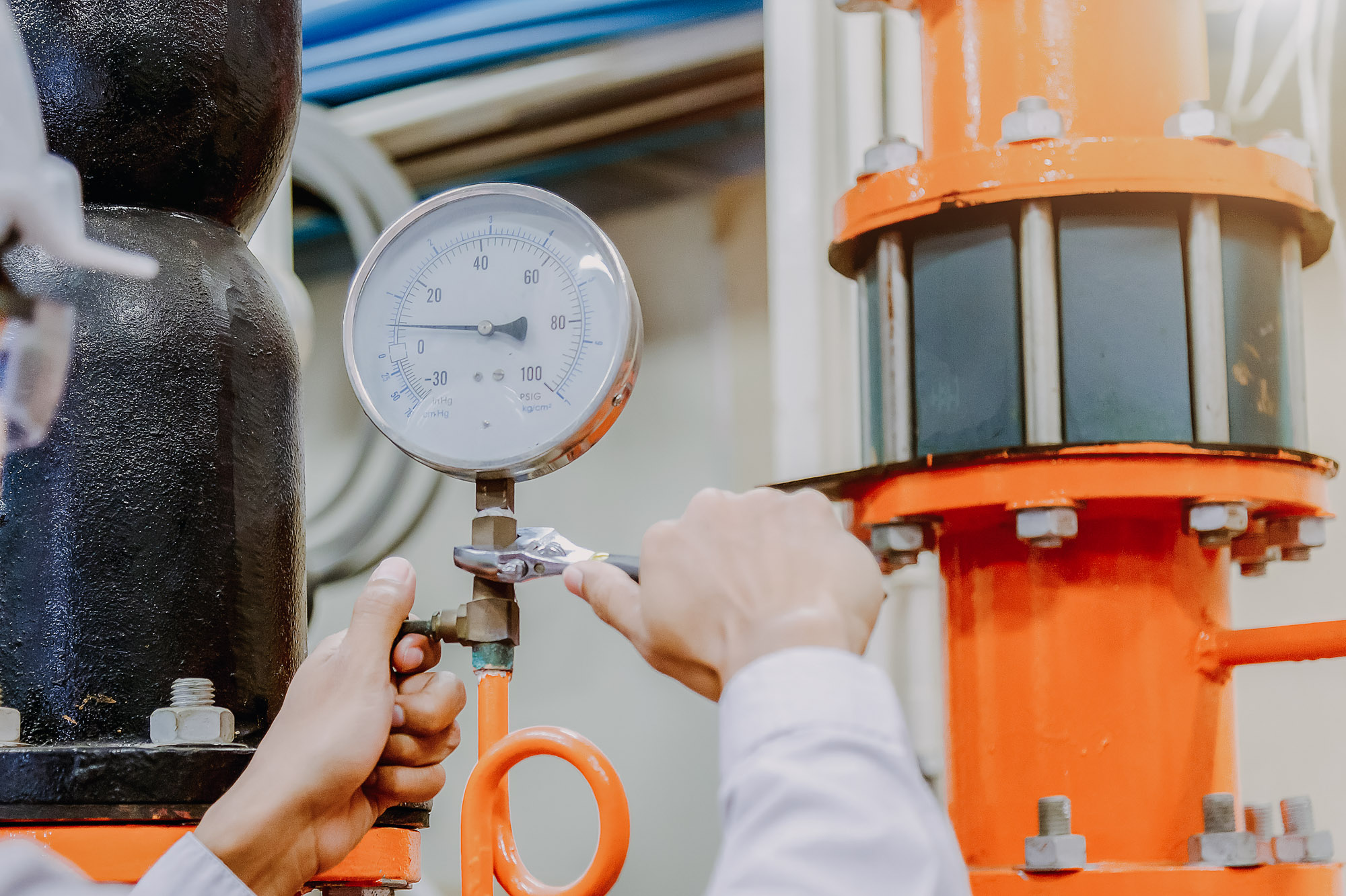 Engineer checking Condenser Water pump and pressure gauge with wrench.