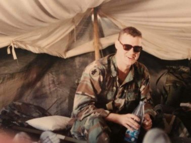 A man in a military uniform sitting in a tent