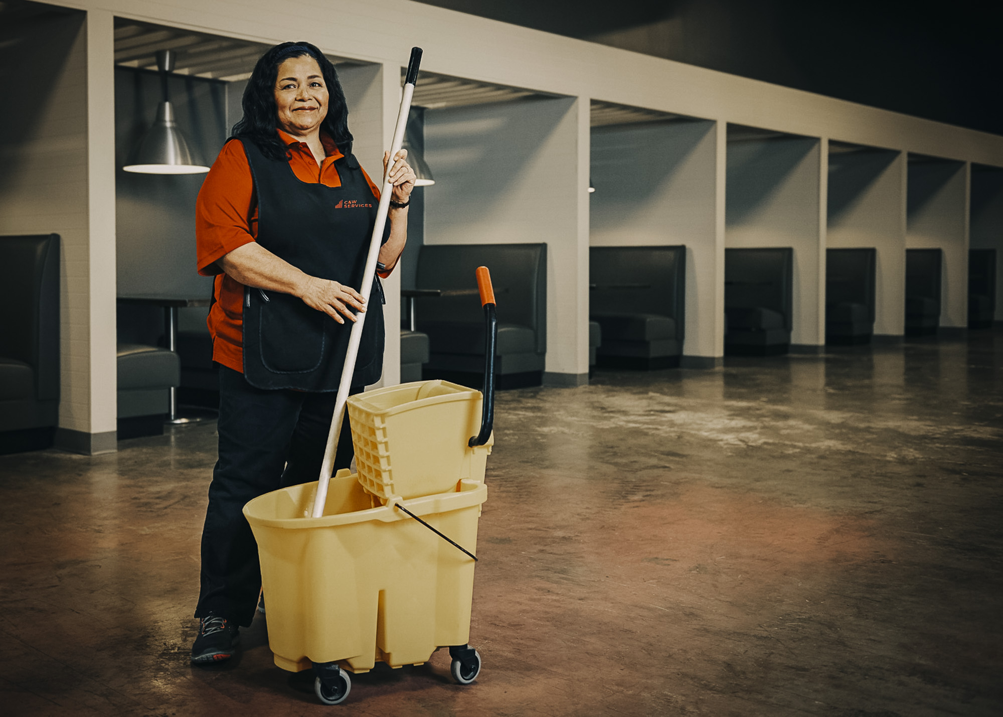 A woman holding a mop and bucket.