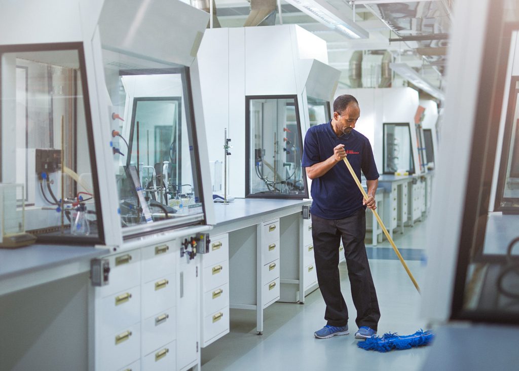 A man mopping a floor in a laboratory.