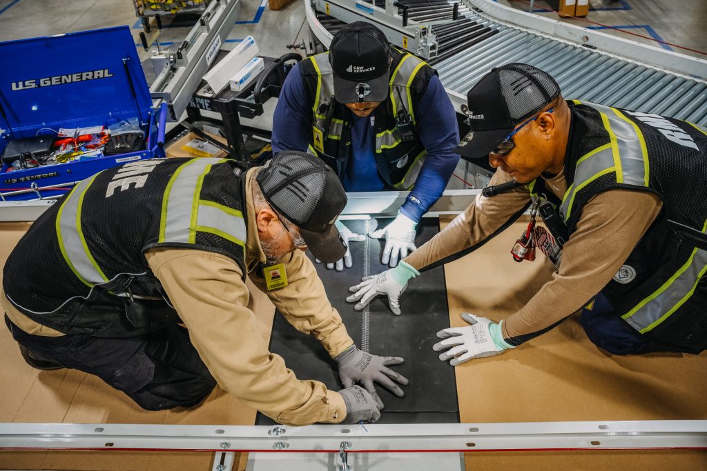 A group of workers repairing a conveyor belt.