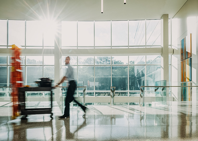 A man walking through a lobby pushing a cart.
