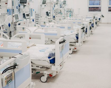 A hospital room with rows of beds and monitors.