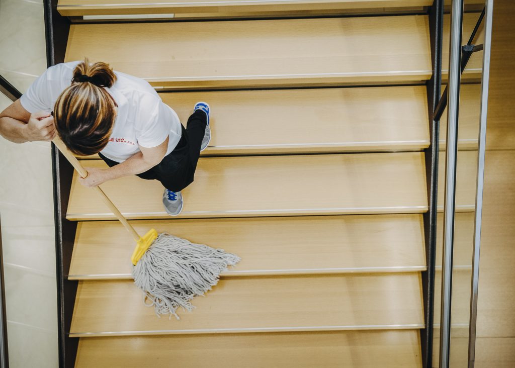 A woman cleaning stairs with a mop.