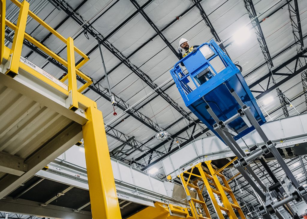 A worker on a lift in a warehouse.