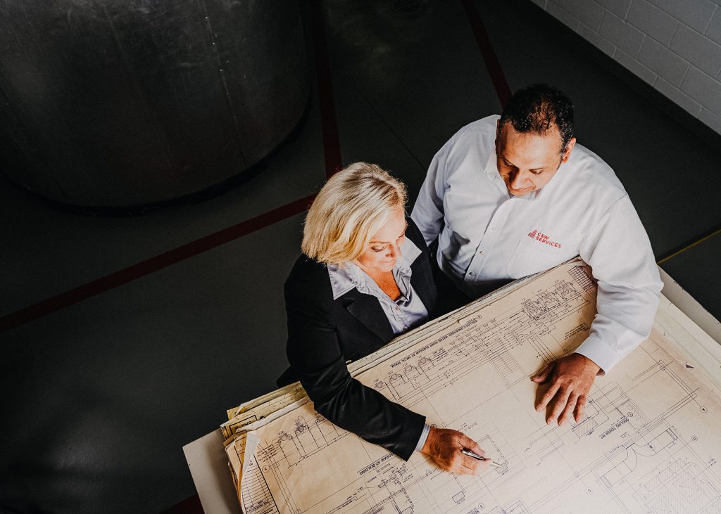 A man and woman looking at a blueprint.
