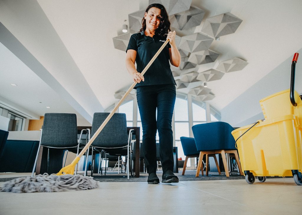 A woman cleaning a floor with a mop.