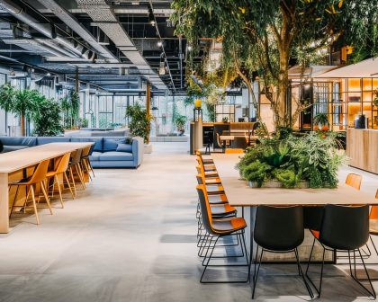 The interior of a modern open office with couches, plants, and tables.
