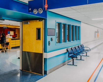 An urgent care corridor with blue walls and chairs.