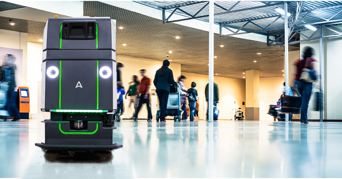 A robot in an airport with people walking around.