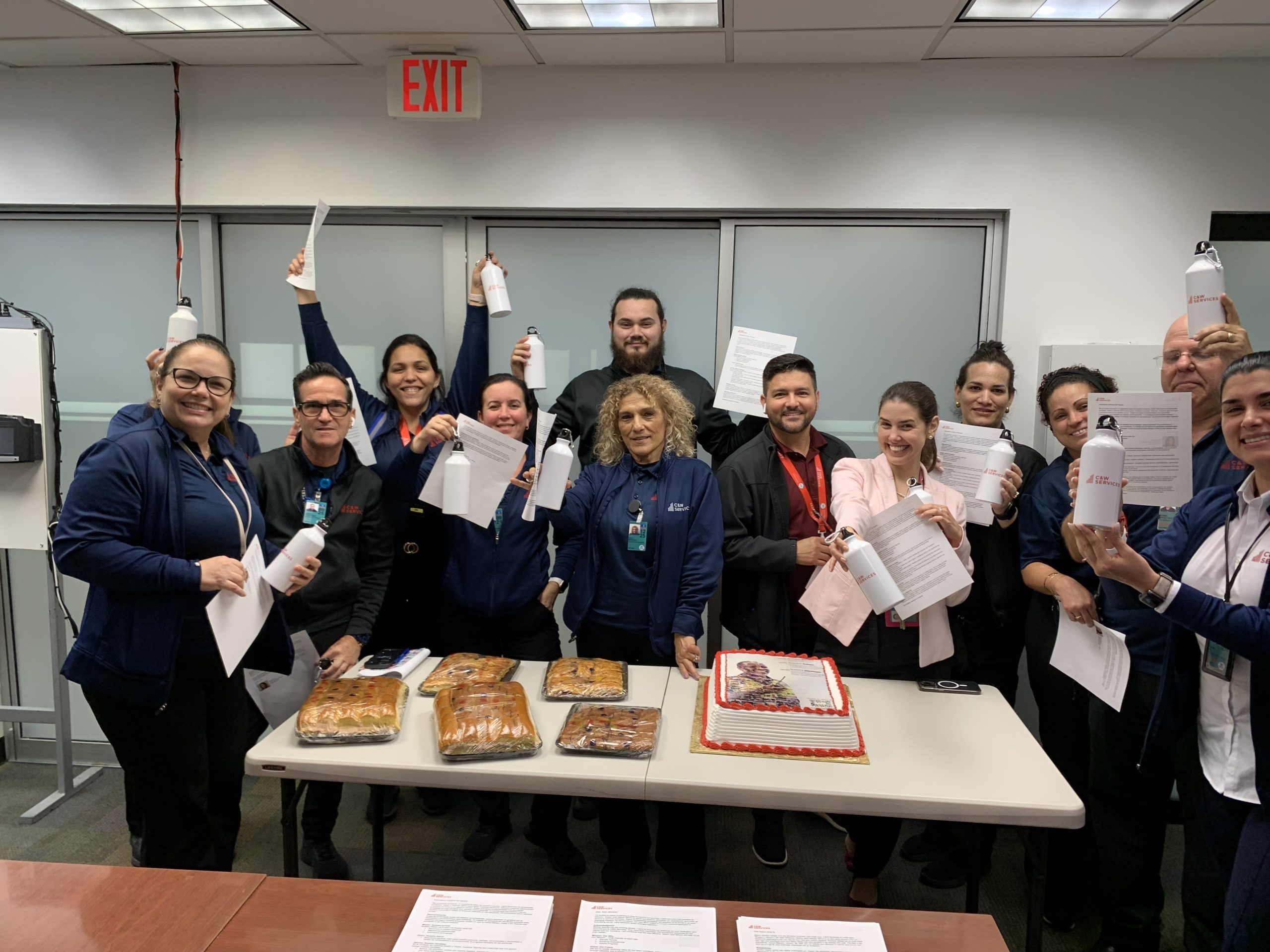 A group of employees celebrating with certificates and cakes in an office setting.