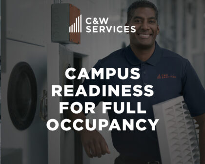 A man in a C&W Services uniform stands indoors holding an air vent, with the text “Campus Readiness for Full Occupancy” overlaid.